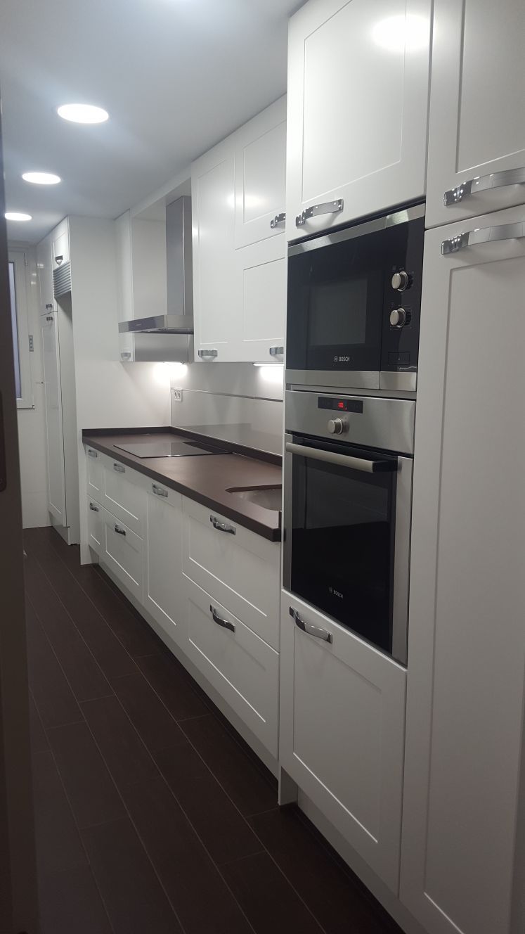 Una cocina con gabinetes blancos y electrodomésticos de acero inoxidable.