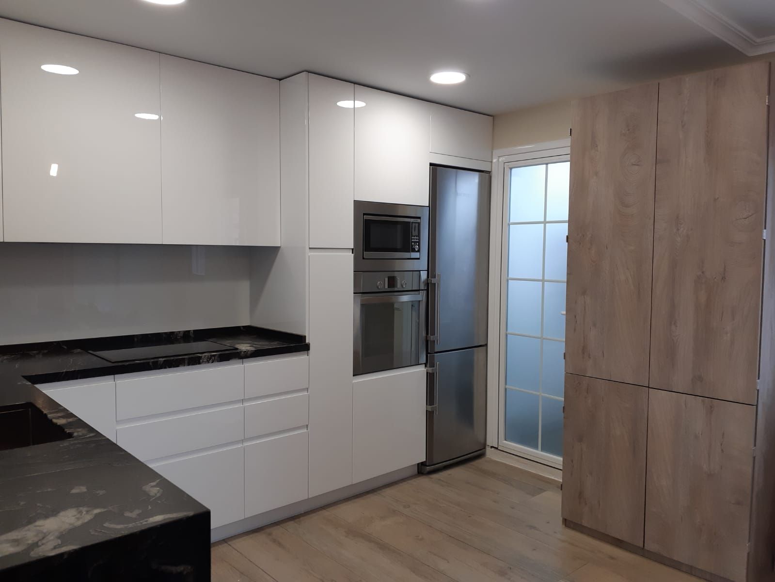 Una cocina con gabinetes blancos y electrodomésticos de acero inoxidable.