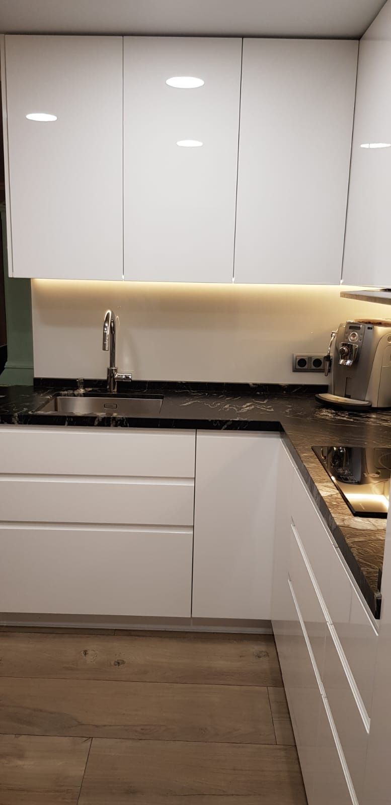 Una cocina con gabinetes blancos, encimeras negras y un fregadero.