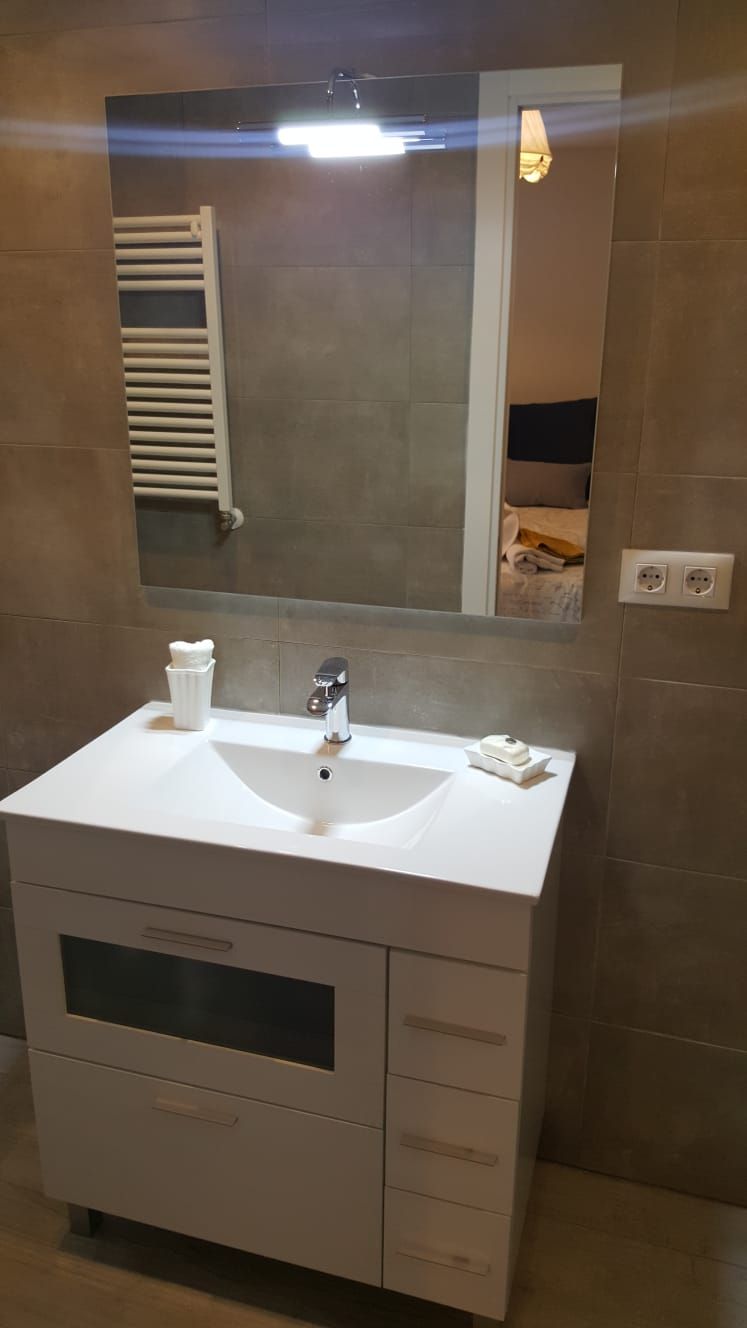 Un baño con lavabo, espejo y toallero.