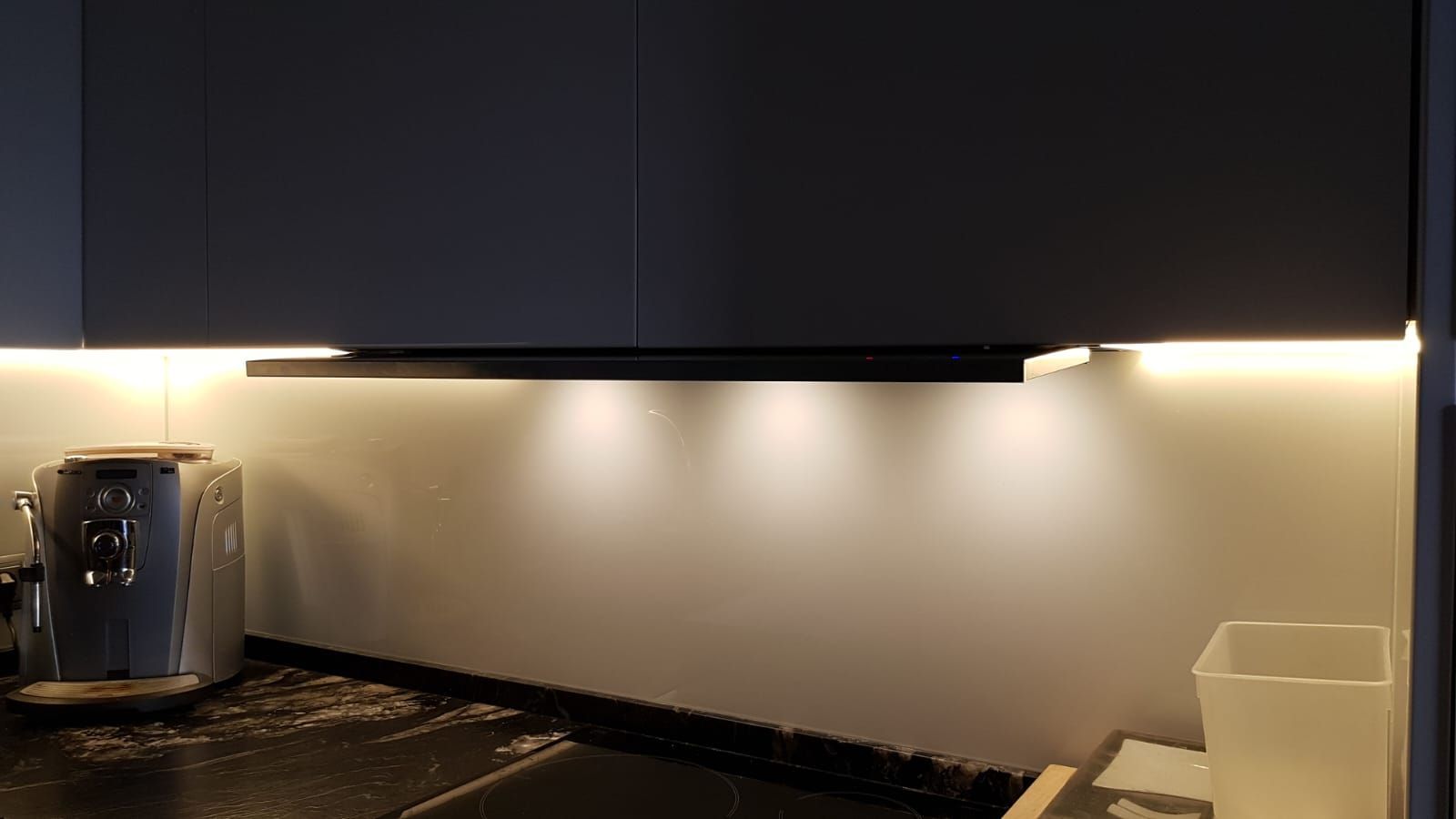 Una cocina con una cafetera y un bote de basura en el mostrador.