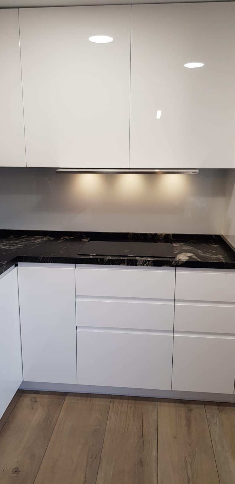 Una cocina con gabinetes blancos y encimeras negras.