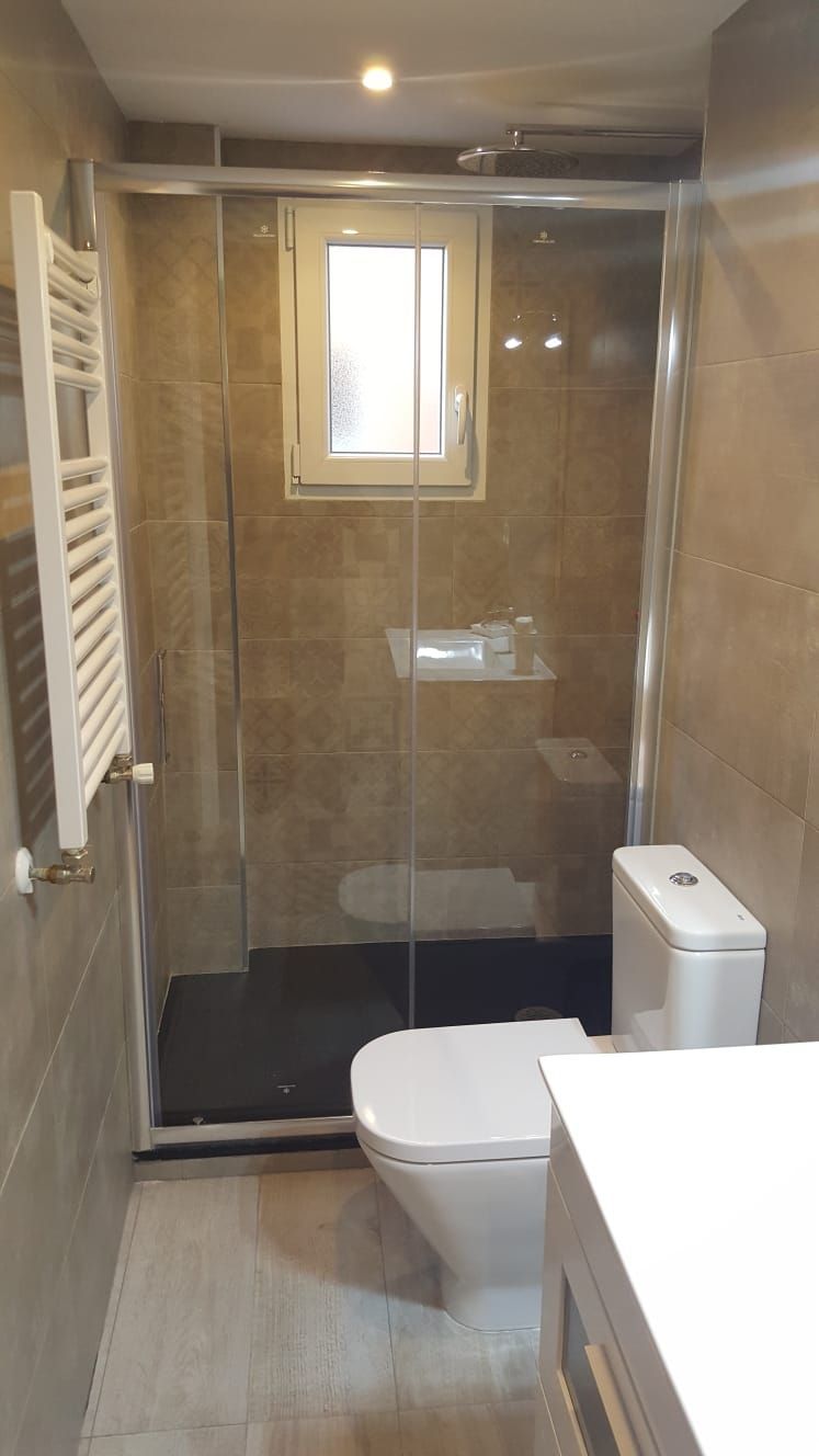 Un baño con inodoro, lavabo, ducha y ventana.