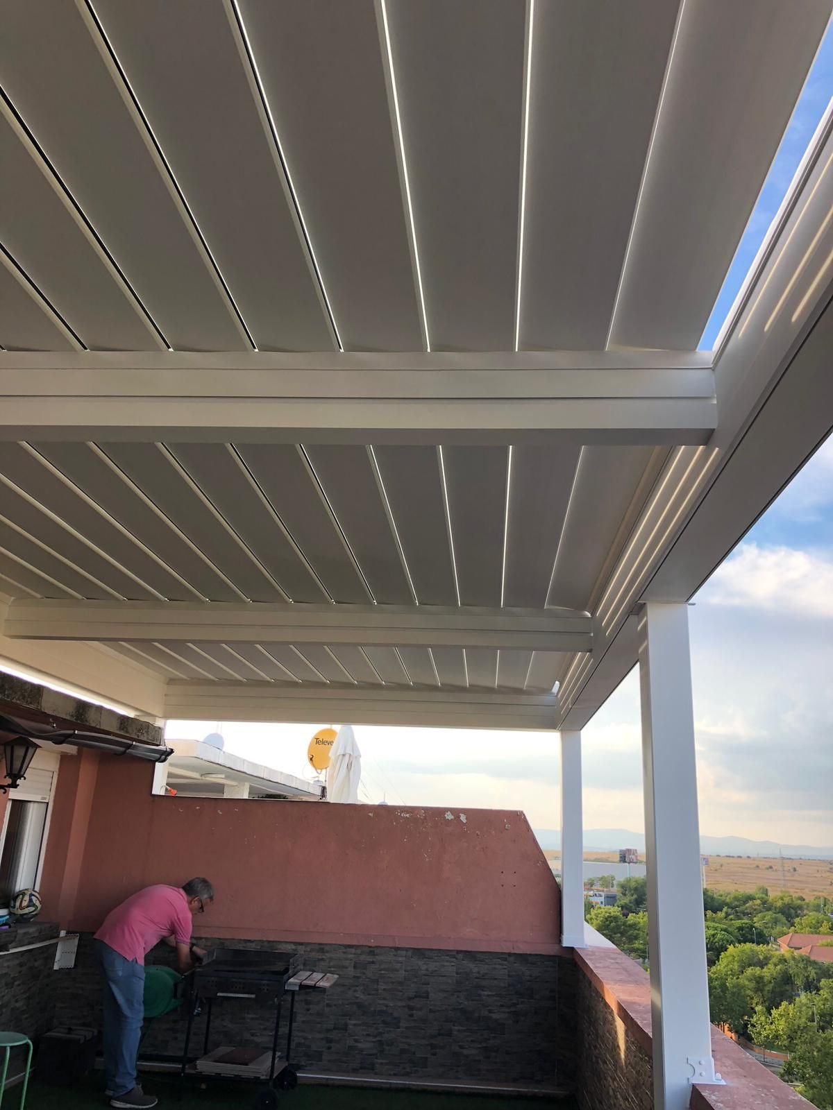 Un hombre está de pie bajo una pérgola blanca en un tejado.