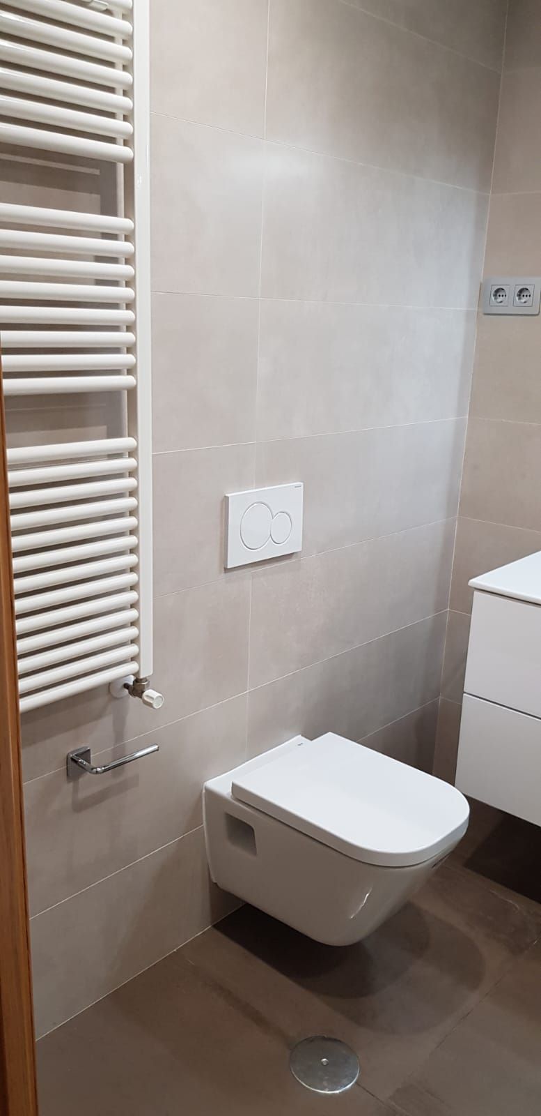 Un baño con inodoro, lavabo y toallero.