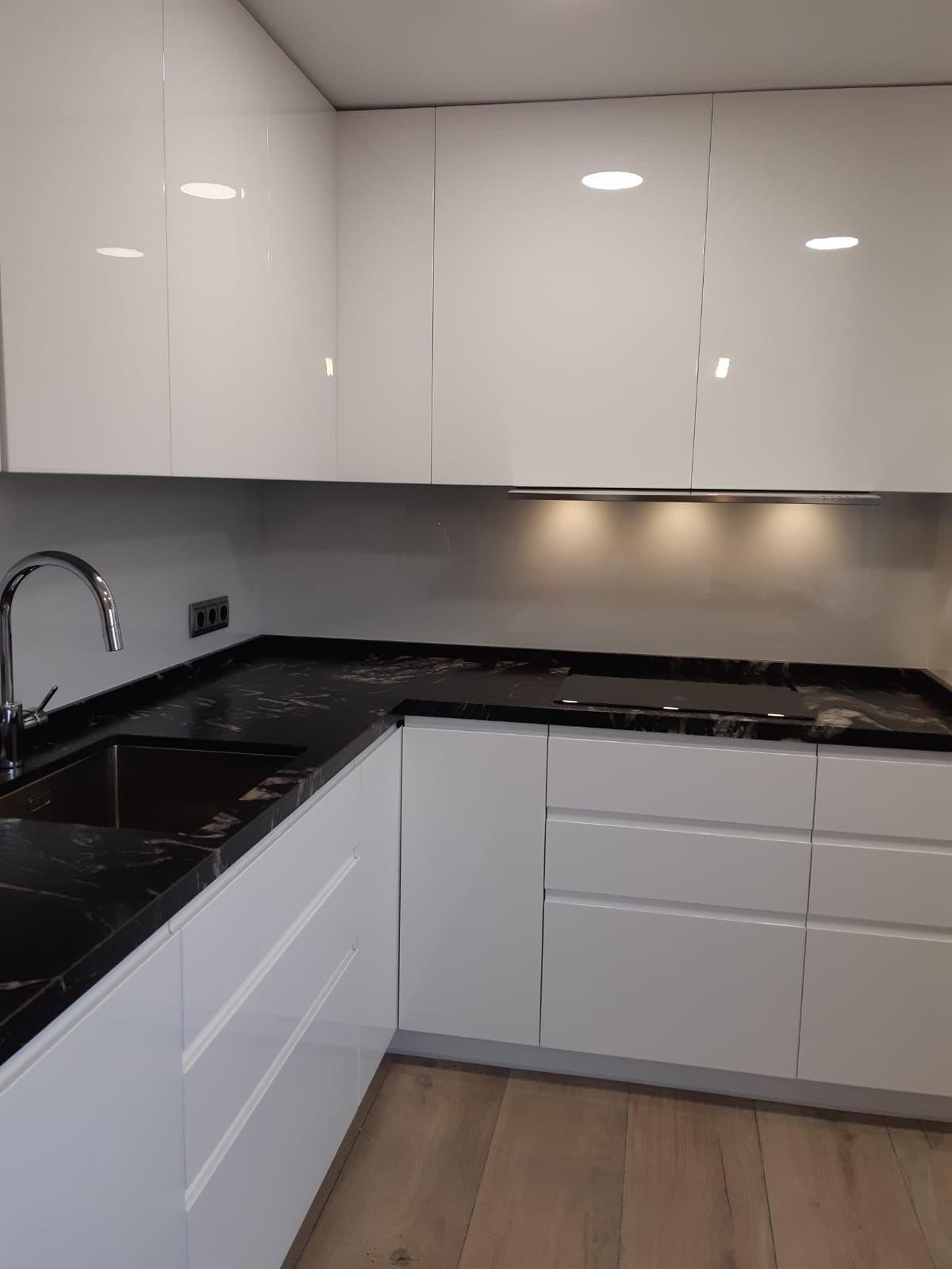 Una cocina con gabinetes blancos, encimeras negras y un fregadero.