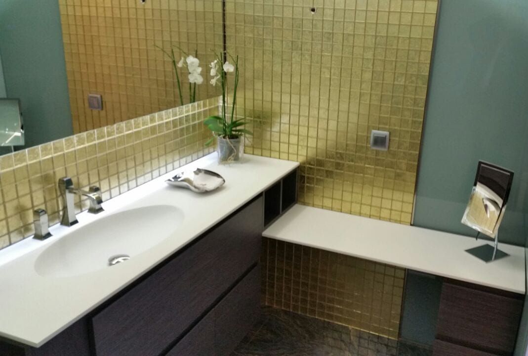 Un baño con lavabo, espejo y banco.