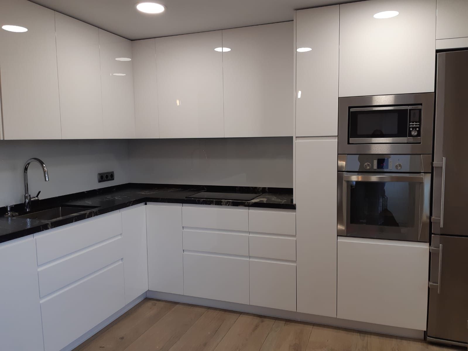 Una cocina con gabinetes blancos y electrodomésticos de acero inoxidable.