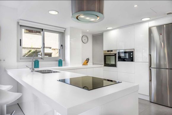 Una cocina con gabinetes blancos y electrodomésticos de acero inoxidable.