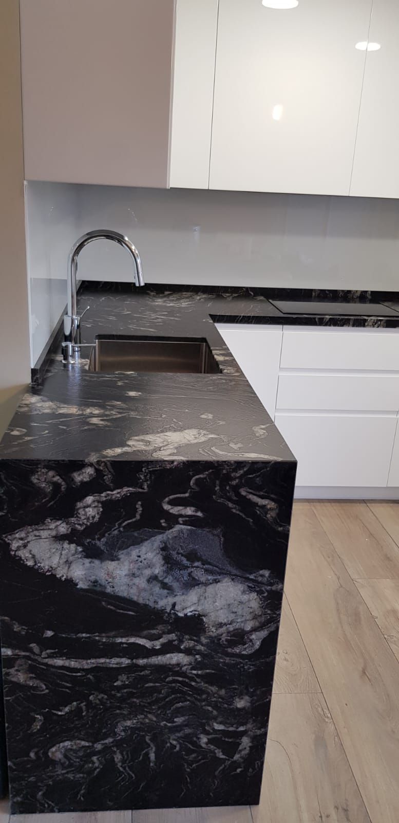 Una cocina con encimera de granito negro y gabinetes blancos.