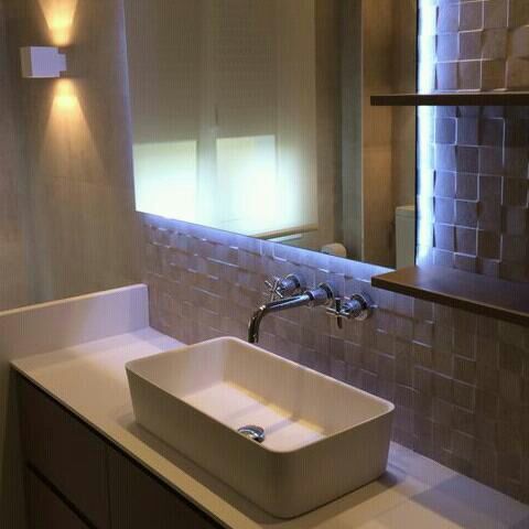 Un baño con lavabo, espejo y estantería.