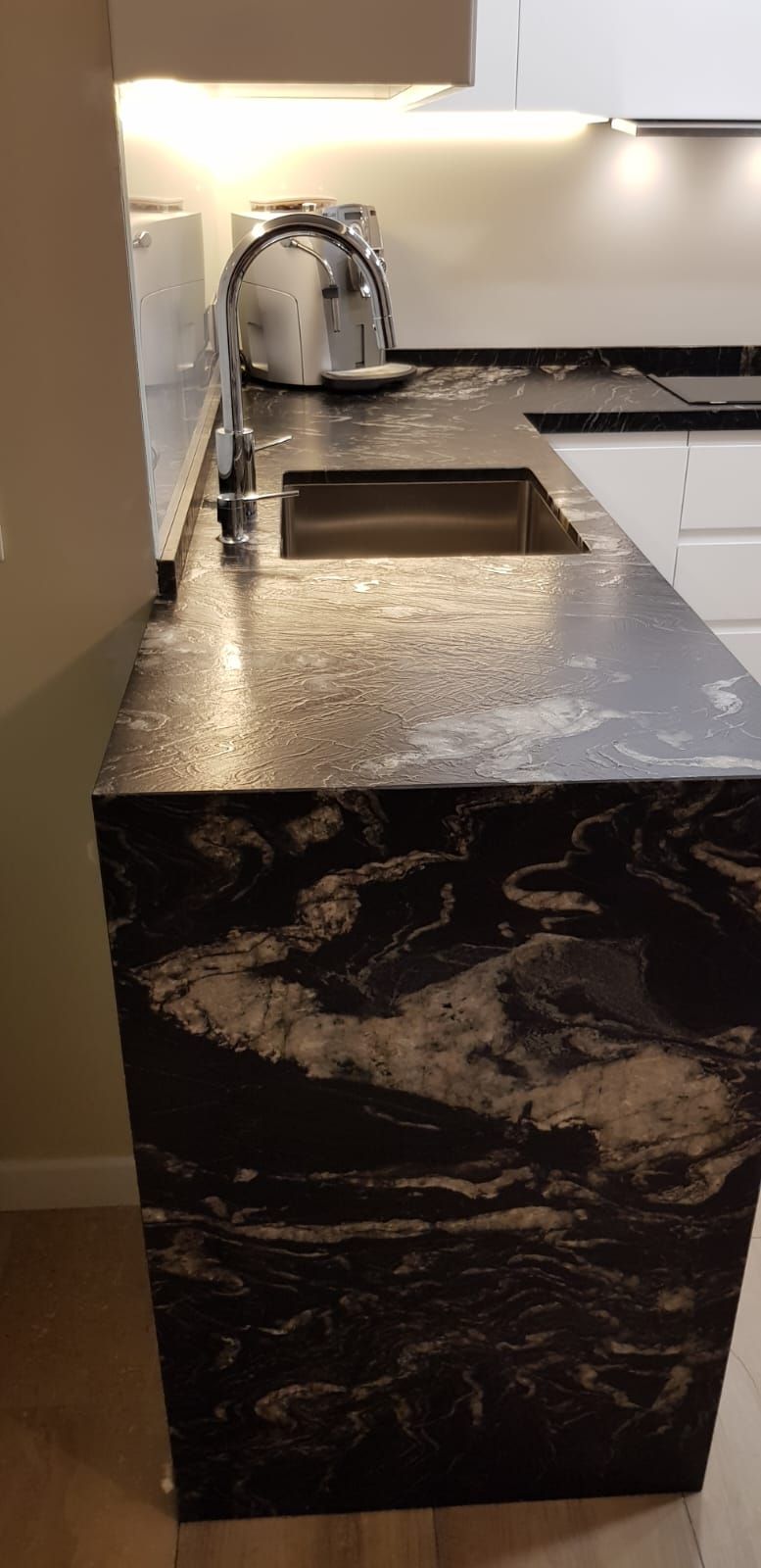 Una encimera de cocina con un fregadero y un grifo encima.