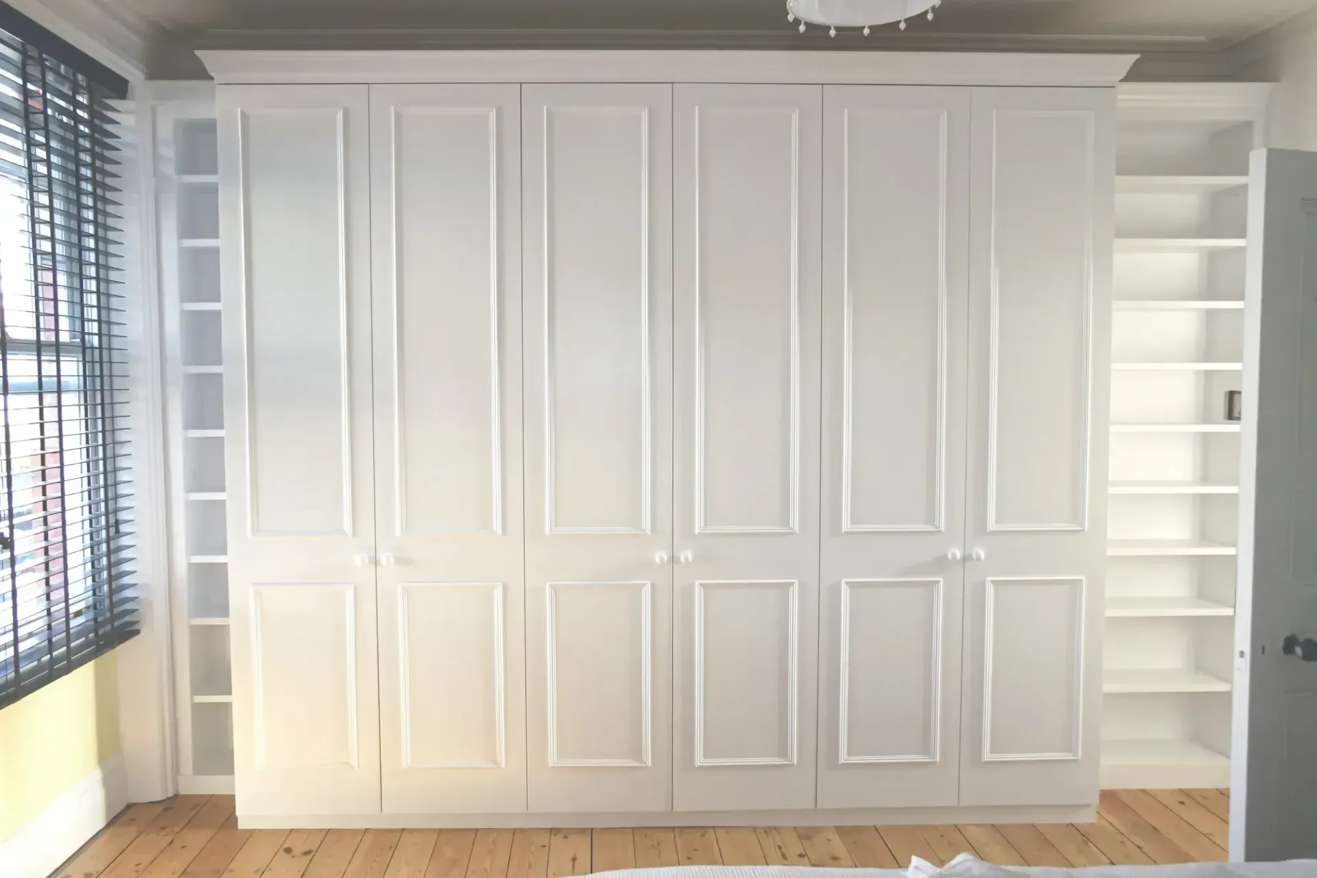 White paneled wall cabinets with open shelves on both sides in a bright room