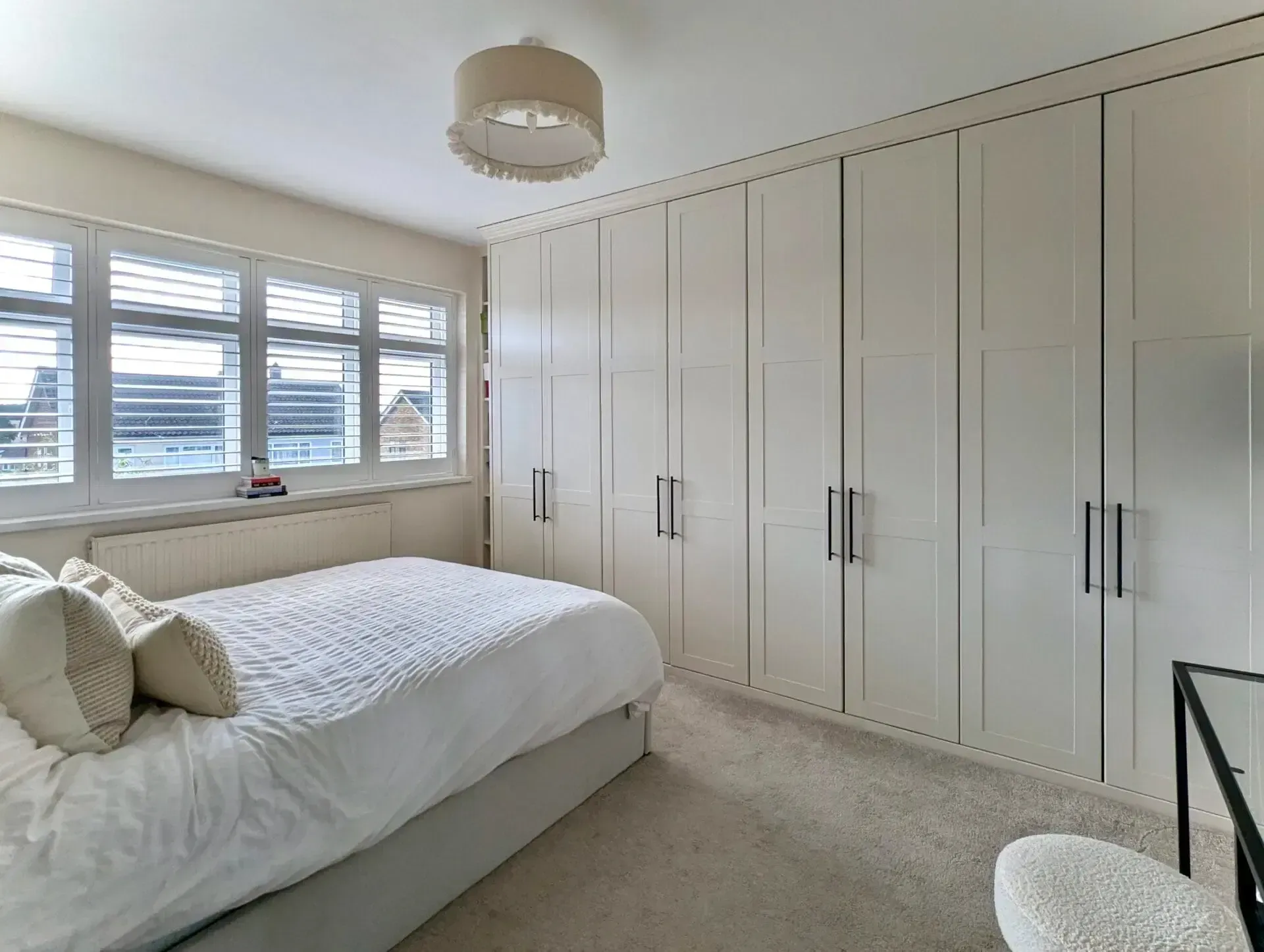 Bright bedroom with built-in wardrobes, white bed, and large window with blinds