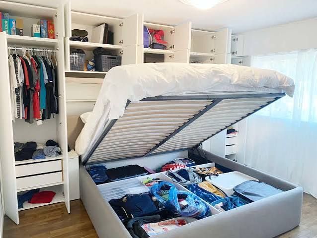 Bedroom with an open storage bed revealing neatly organized clothes and items inside the base.