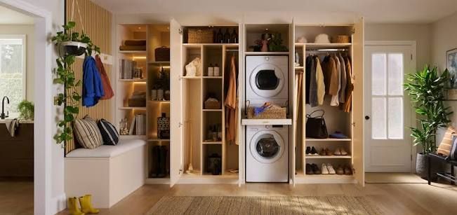 Bright walk-in closet with shelves, hanging clothes, a washer and dryer, and a plant by the window