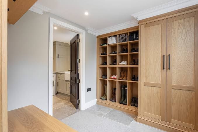 Bright bedroom with built-in wooden wardrobes and open shelving beside a doorway to a bathroom