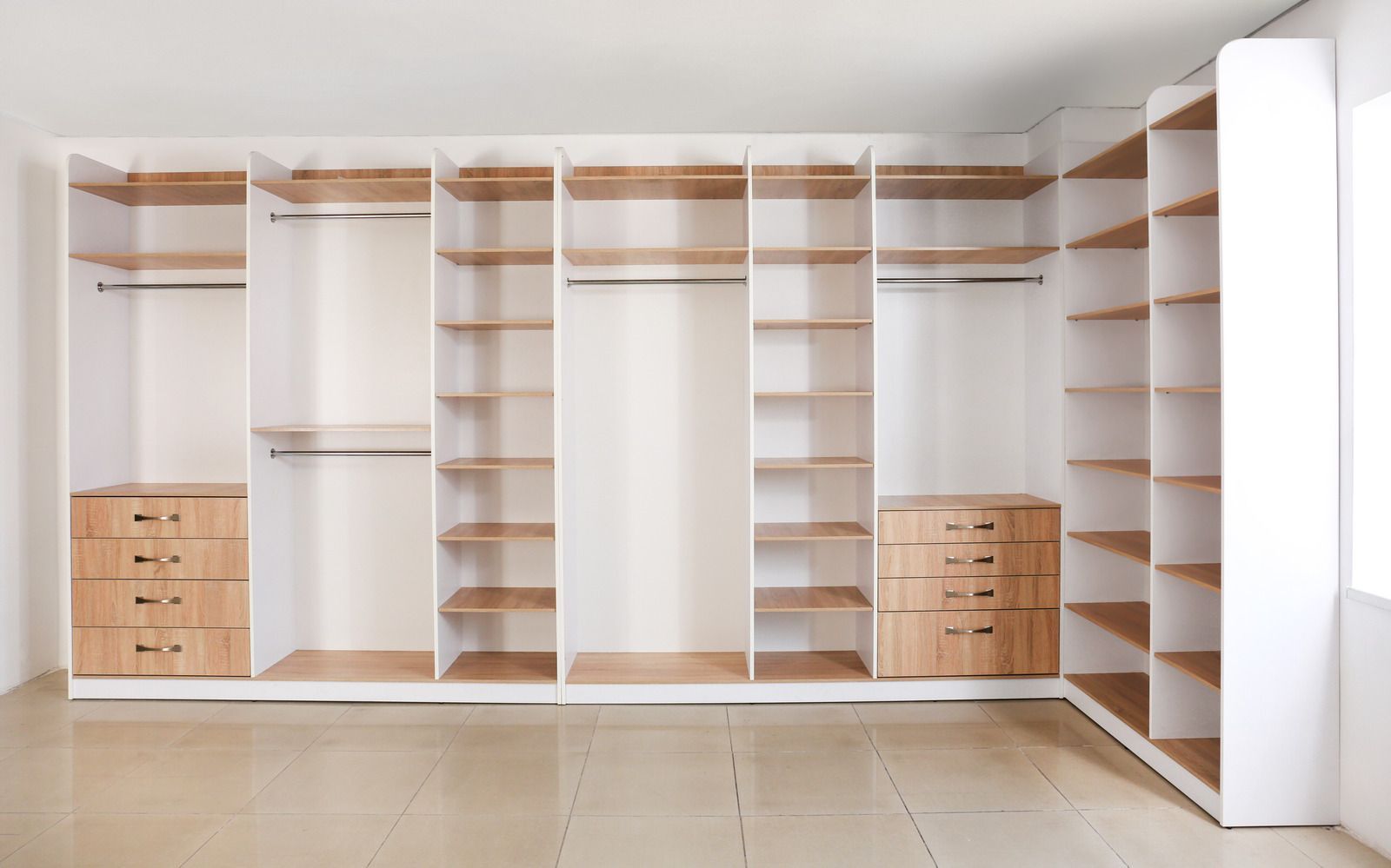 Built-in white closet with open shelves, hanging rods, and small wooden drawers in a bright room