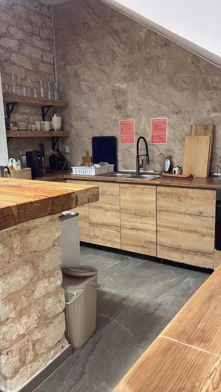 Cocina con muebles de madera, pared de piedra y grifería de metal.