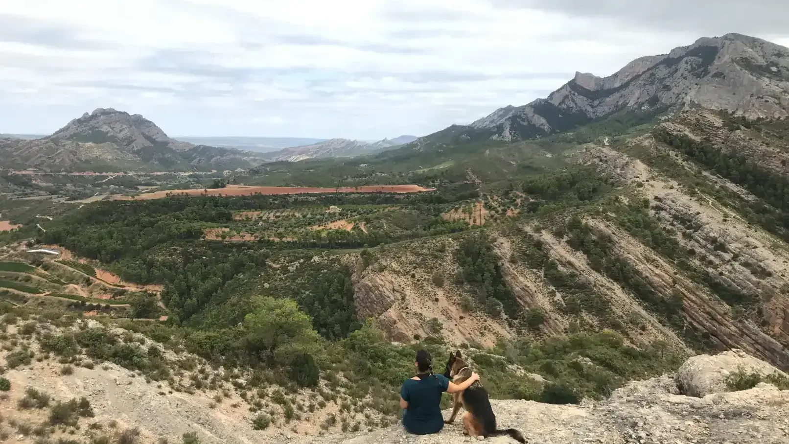 Un hombre y un perro están sentados en la cima de una montaña.