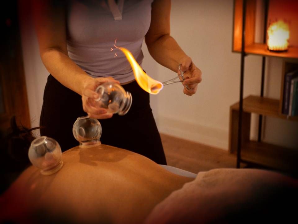 La personne recevant une thérapie par ventouses, le thérapeute utilisant une flamme pour créer une succion.