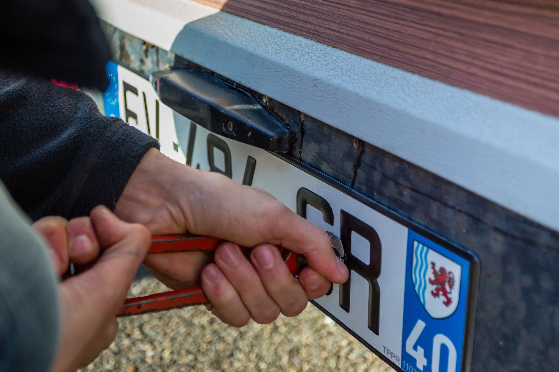 Démontage de plaque d'immatriculation par un mécanicien.