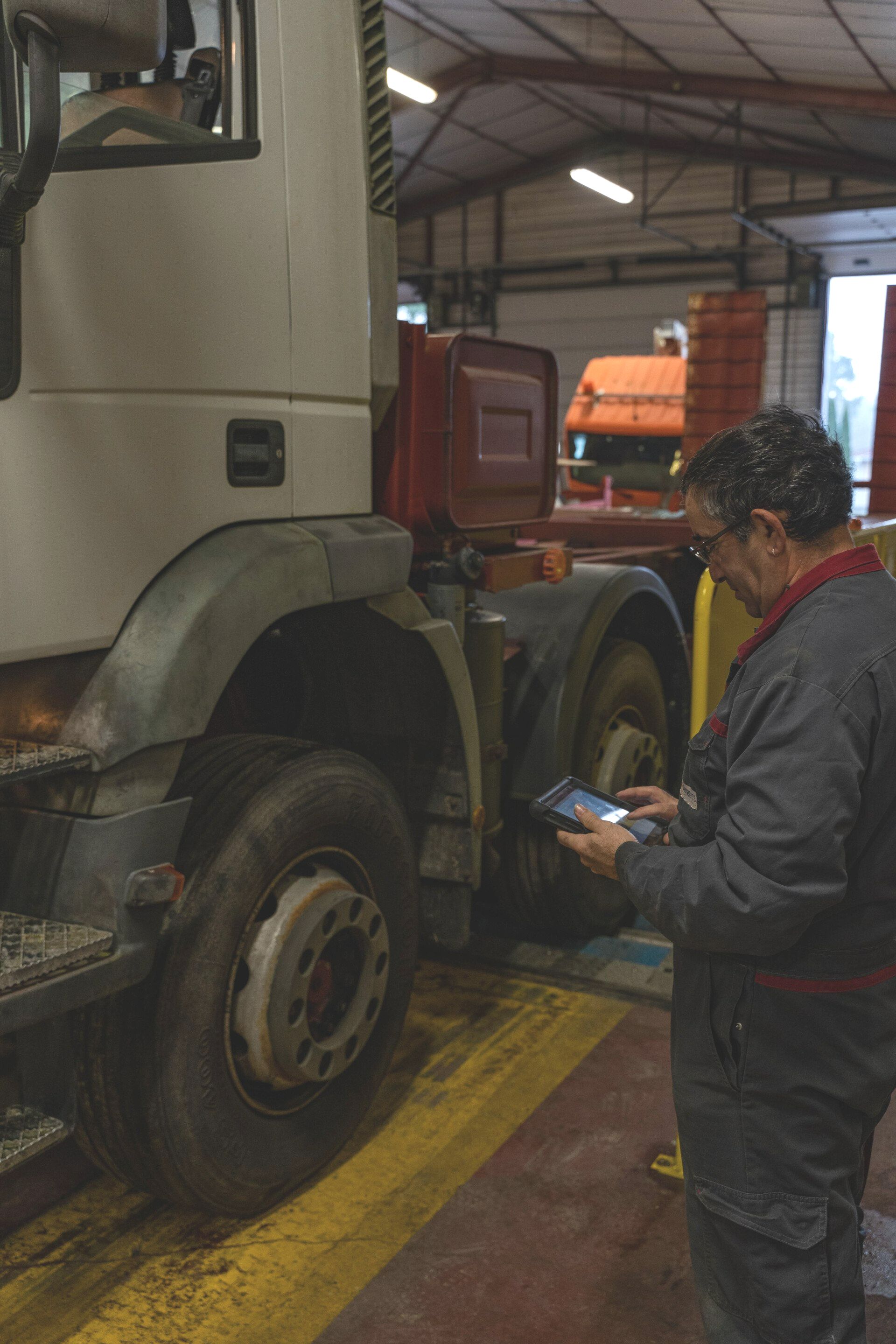 Un mécanicien effectuant un diagnostic à l'aide d'une tablette sur un camion.