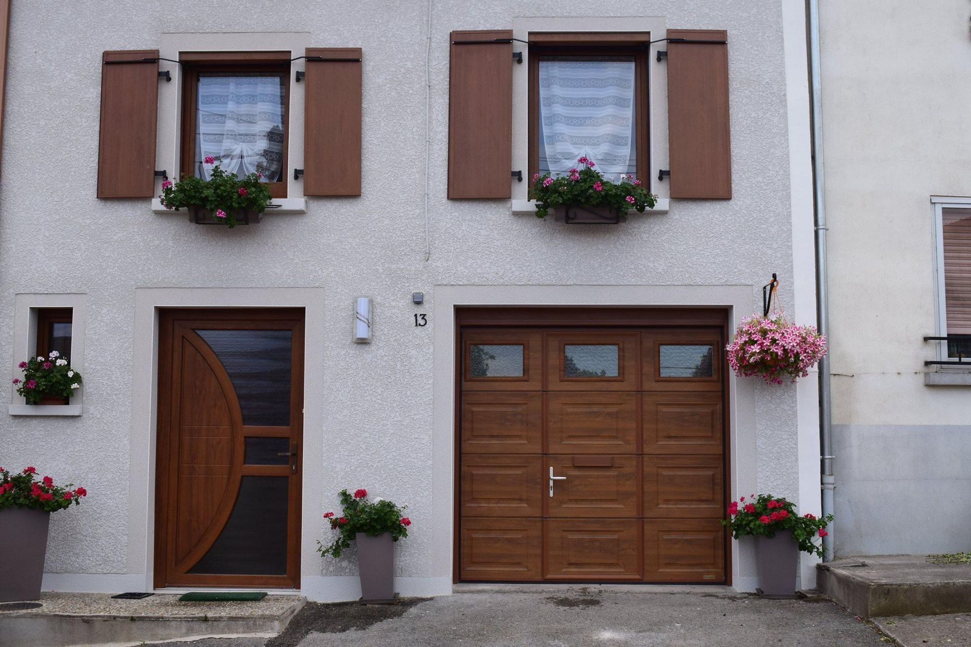 Vue extérieure d'une maison avec garage, porte et deux fenêtres avec volets battants