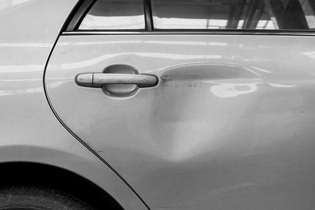 Gros plan sur la portière arrière et la poignée d’une voiture argentée.