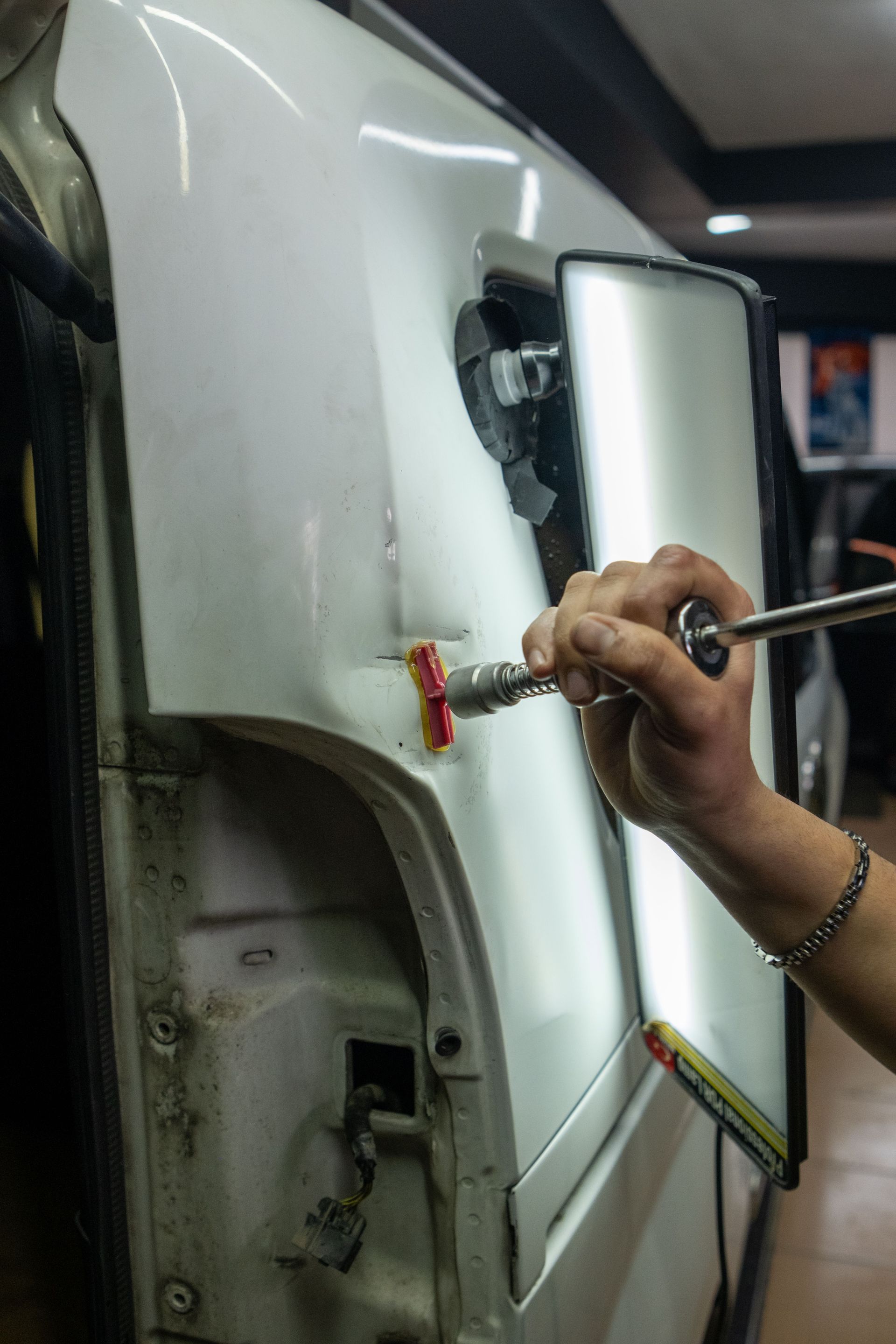 Ponçage manuel d’un panneau de carrosserie blanc près d’une ouverture de garniture