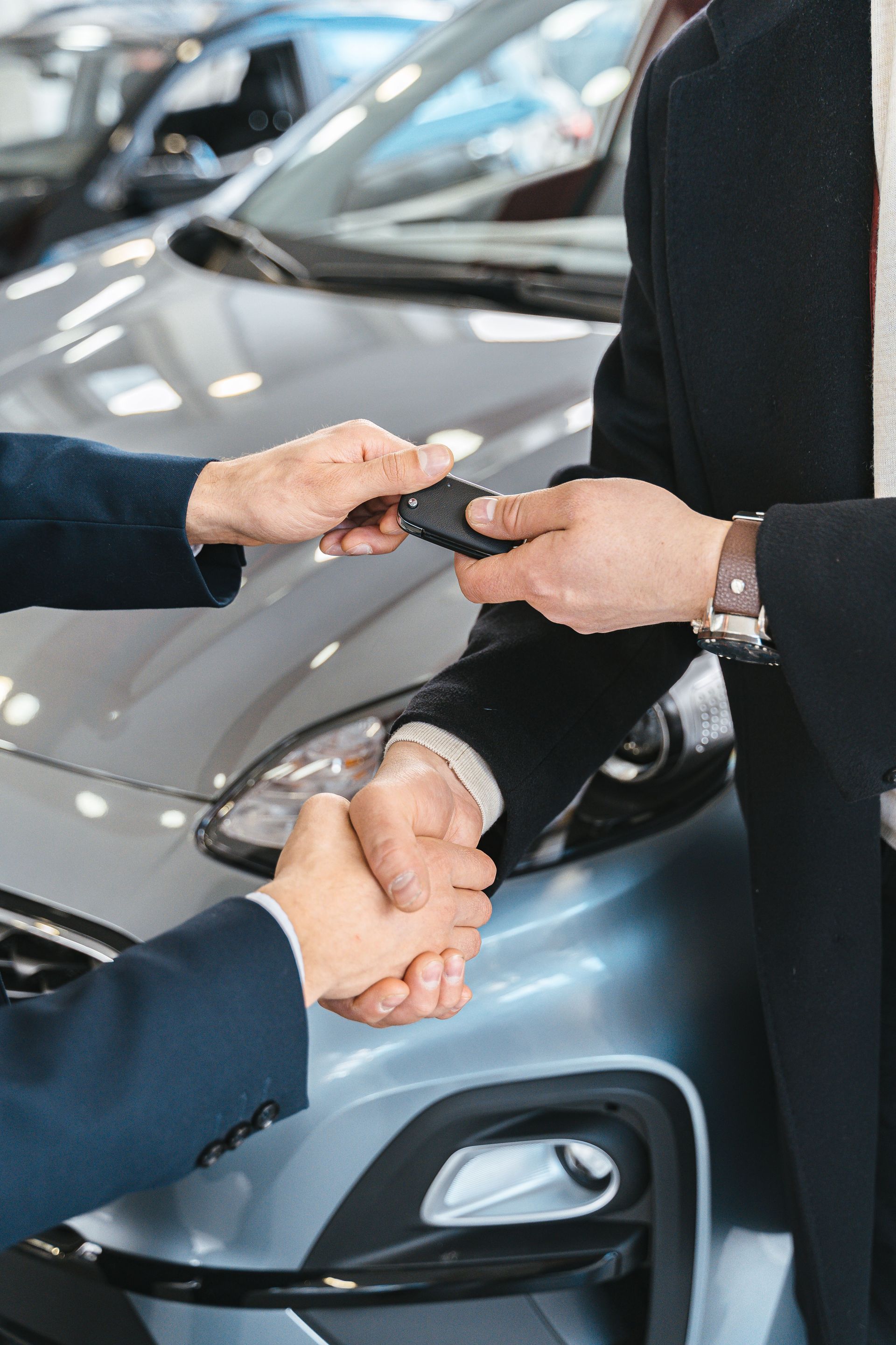 Des clés de voiture remises à côté d’une voiture grise dans le showroom d’une concession automobile