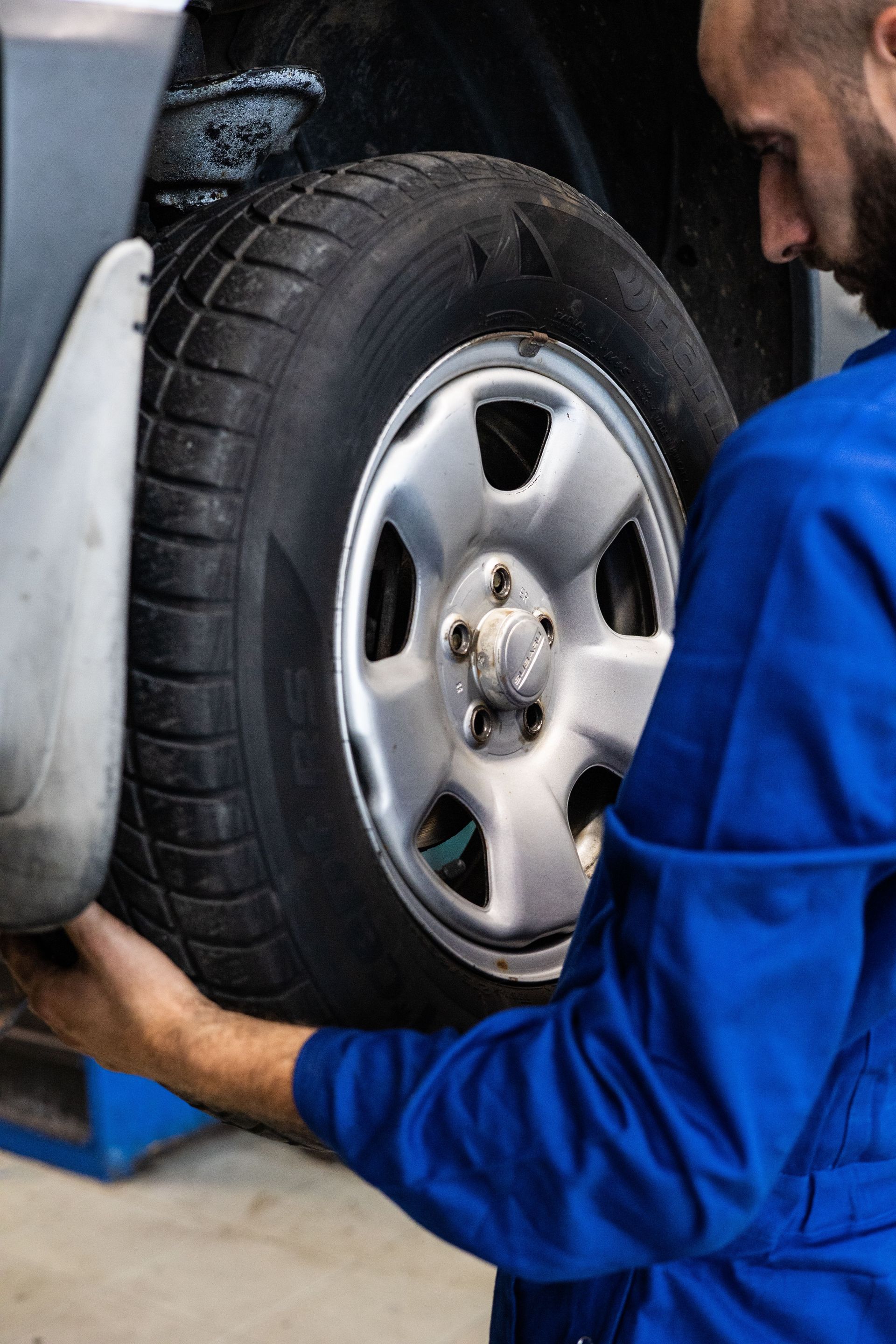 Un mécanicien en chemise bleue ajuste un pneu de voiture dans un garage
