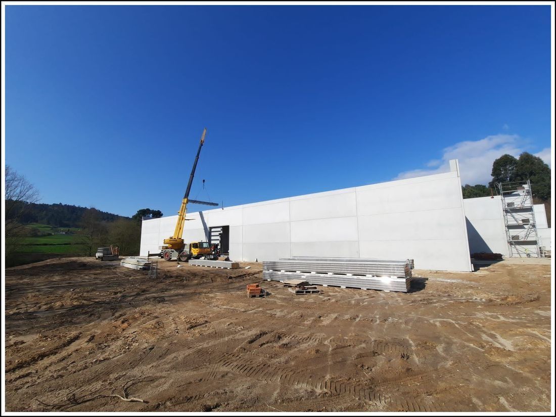 Se está construyendo un gran edificio blanco en un campo de tierra.