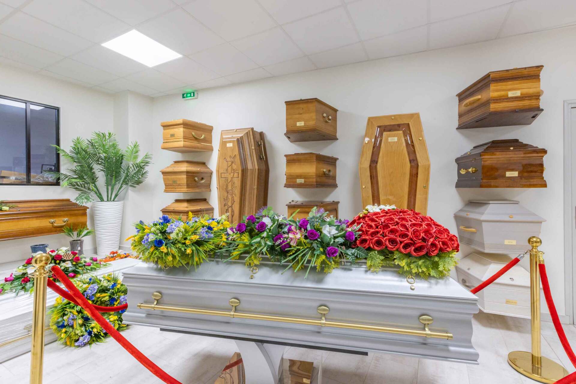 Présentation de différents cercueils, dont  un orné de fleurs