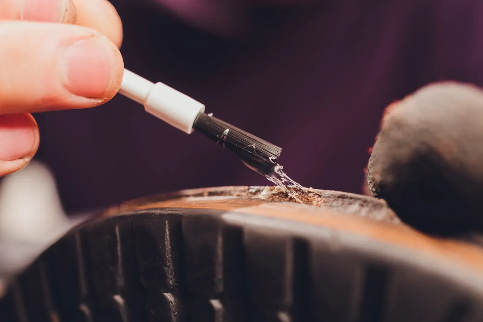 Schuhcreme von Hand mit einem kleinen Pinsel auf einen schwarzen Schuh auftragen
