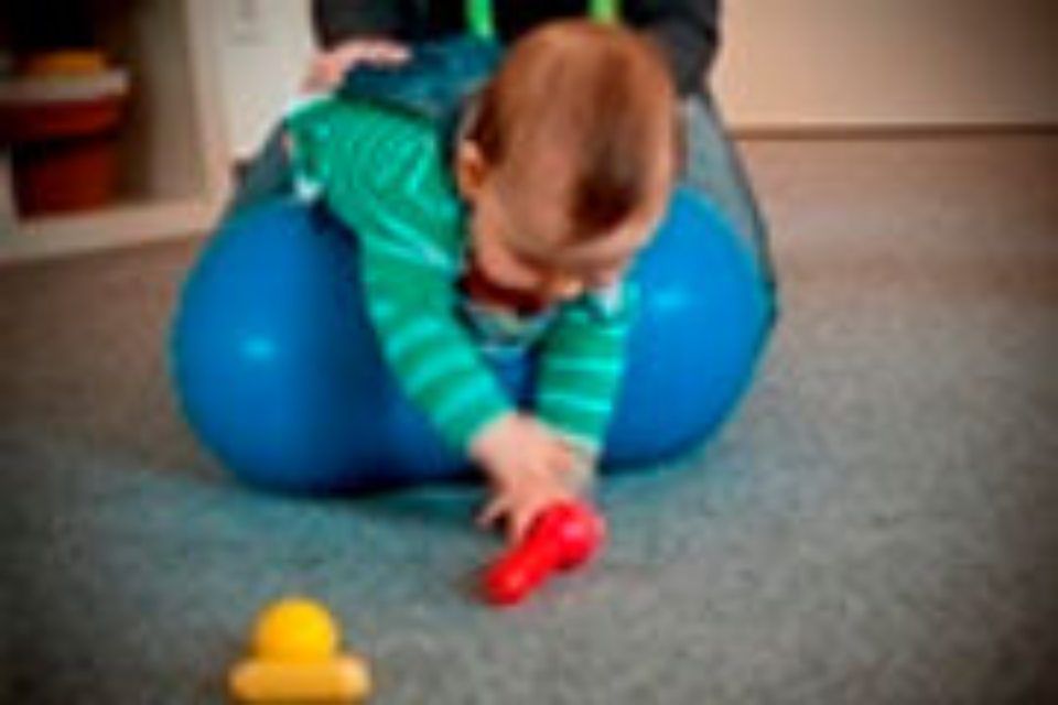 Praxis für Ergotherapie und Logopädie Brückner - Kleinkind auf einem Gymnastikball beim Spielen