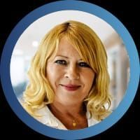 Une femme portant une chemise blanche et un badge avec son nom sourit à la caméra