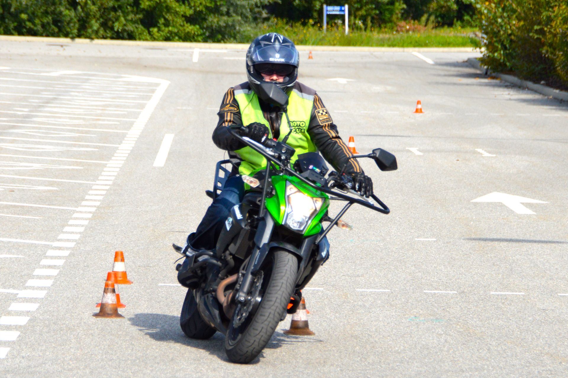 Apprenti motard sur une moto verte qui fait des exercices de conduite