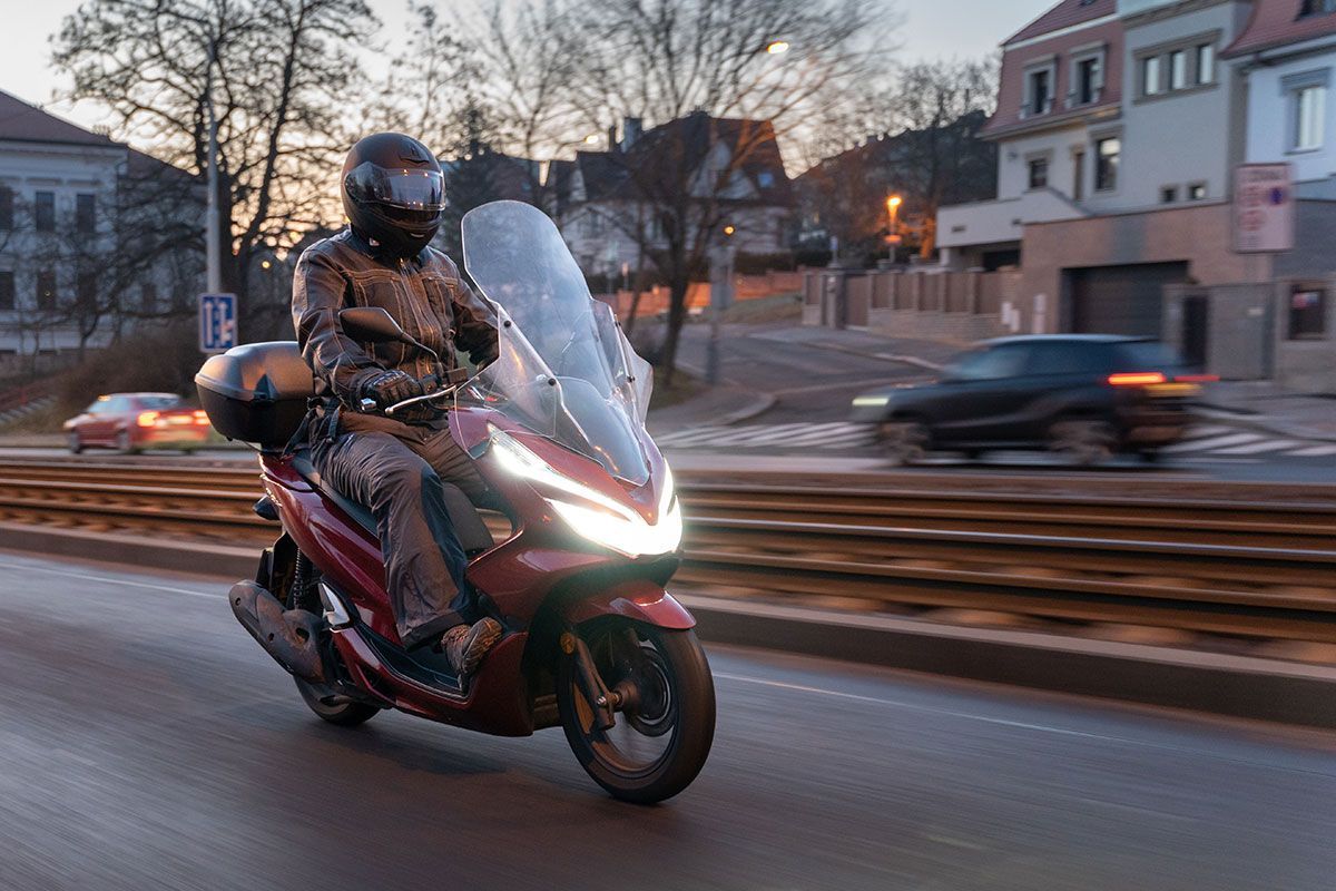 Homme qui conduit un scooter rouge en ville