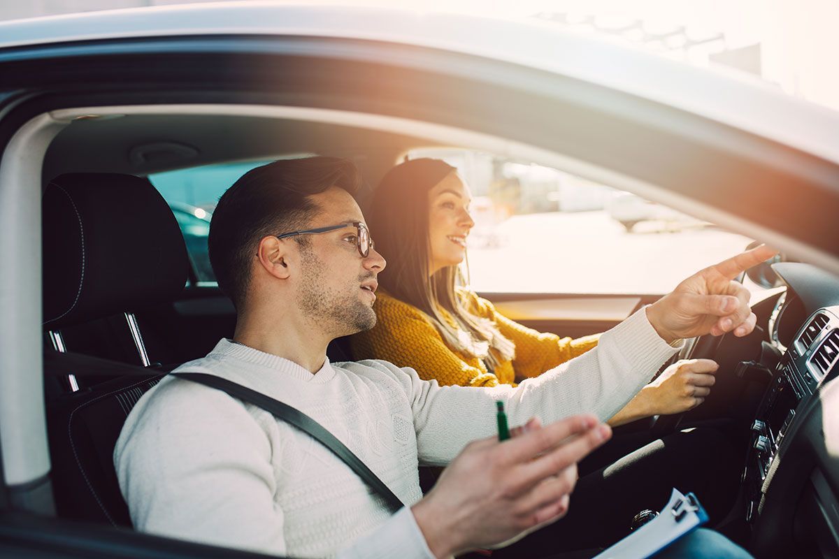 Moniteur d'auto-école qui donne une leçon de conduite à une jeune femme