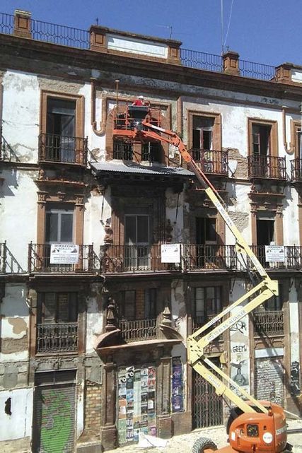 Un hombre está trabajando en el tejado de un edificio con una grúa.