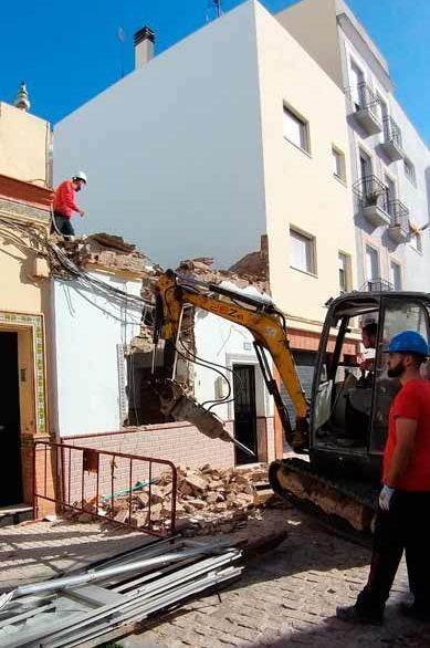 Un hombre está parado frente a un edificio que está siendo demolido.
