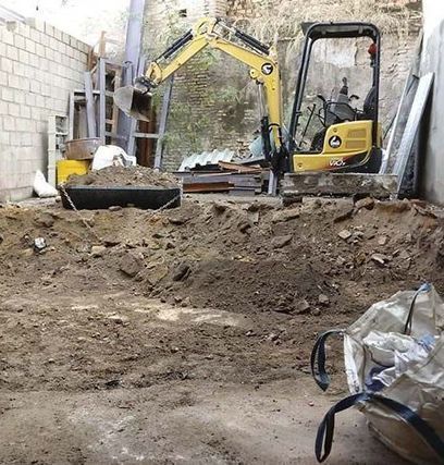 Una excavadora amarilla está cavando en un montón de tierra.