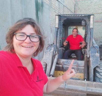 Una mujer se toma un selfie con un hombre sentado en una excavadora.