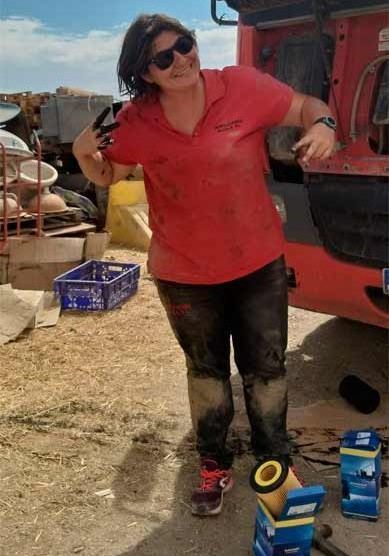Una mujer con una camisa roja está parada frente a un camión.