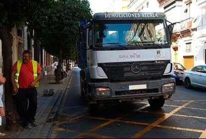 Un camión Mercedes está estacionado al costado de la carretera al lado de un árbol.