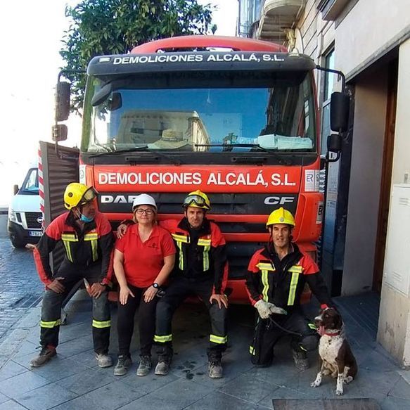 Un grupo de personas posando para una foto delante de un camión de Demoliciones Alcalá SL