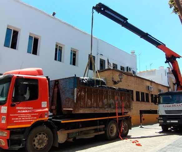 Un camión con una grúa acoplada está estacionado frente a un edificio.