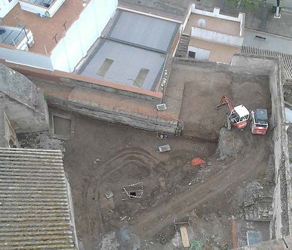 Una vista aérea de un sitio de construcción con edificios al fondo.