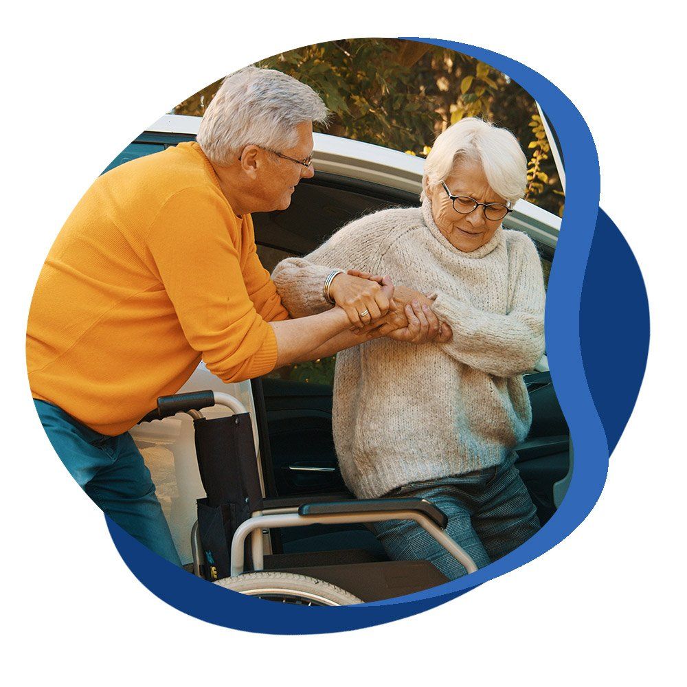 Un homme âgé aide une dame à s'installer dans son fauteuil roulant